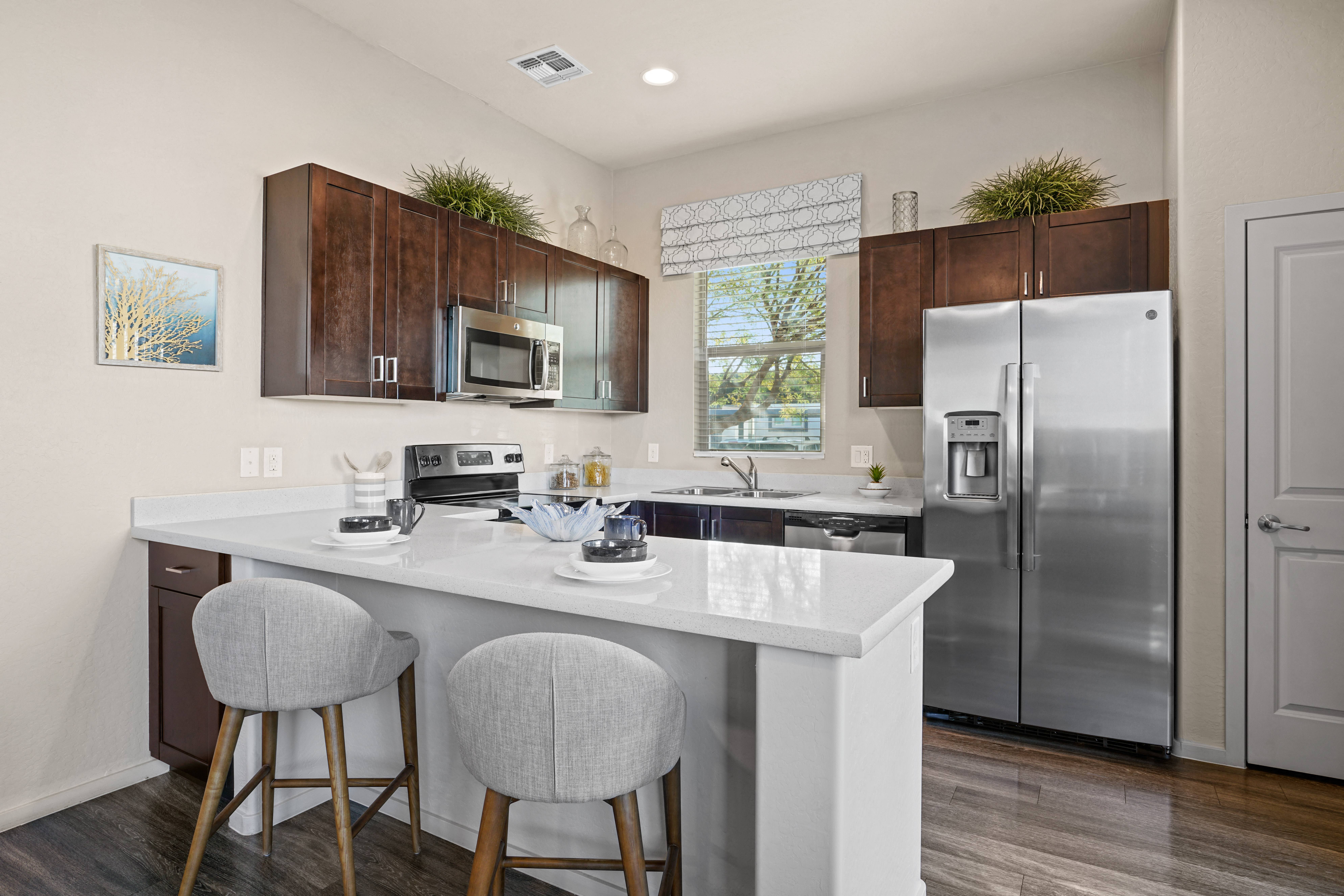 a kitchen with stainless steel appliances and a counter with two stools at Olive Queen Creek Apartments, Arizona